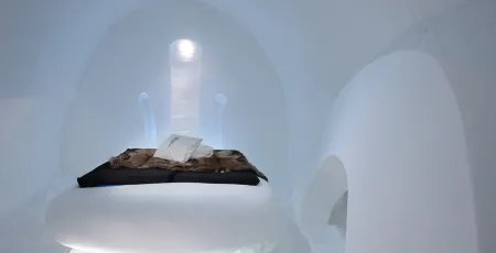 dubbelsäng med renfällar i en svit av snö och is på Icehotel