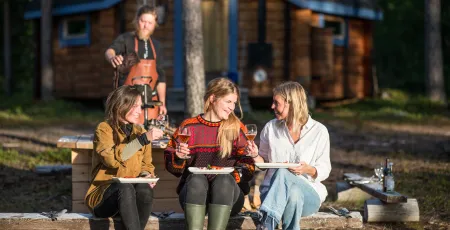 Three woman sitting on a bench in the wilderness